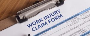 This image shows a workers compensation injury form on a clipboard being filled out by a Concord workers' compensation lawyer