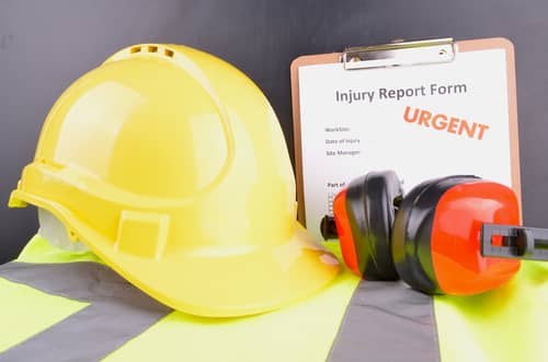 A hard hat and a work injury report form marked urgent