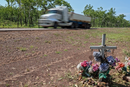 Transfer truck passing a grave marker on the roadside symbolizing the impact of deadly truck accidents in Asheville.