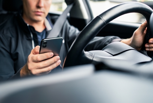 Gastonia rideshare driver checking phone for ride request — used by a Gastonia rideshare accident lawyer to illustrate distracted driving risks in Uber and Lyft cases.