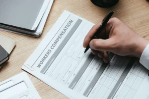 NC Industrial Commission Form 18 and workers compensation claims assistance paperwork on desk with pen