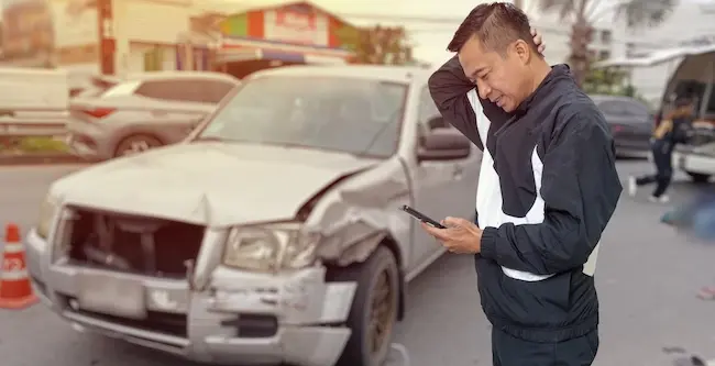 A business vehicle crashes with a victim on the phone, reporting a collision involving a company car at the accident scene.