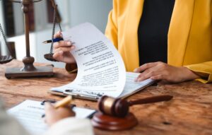 Personal injury lawyers from 1 Charlotte Injury Lawyers are reviewing legal documents and case files with the scales of justice to their right and a gavel to their left.