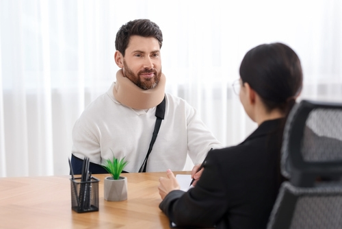 A man wearing a neck brace has a consultation with a personal injury lawyer.